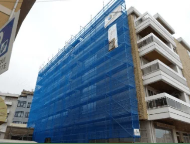 Edifício de habitação com andaimes e rede de proteção durante obras de reabilitação da fachada